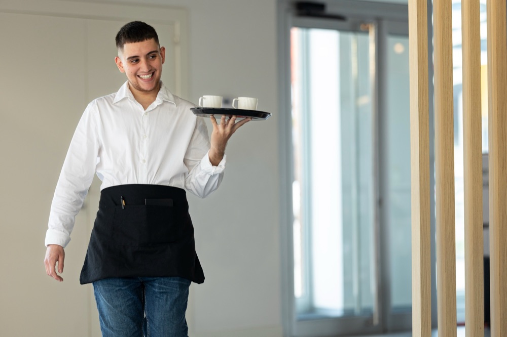 Trained service staff carrying a tray of drinks